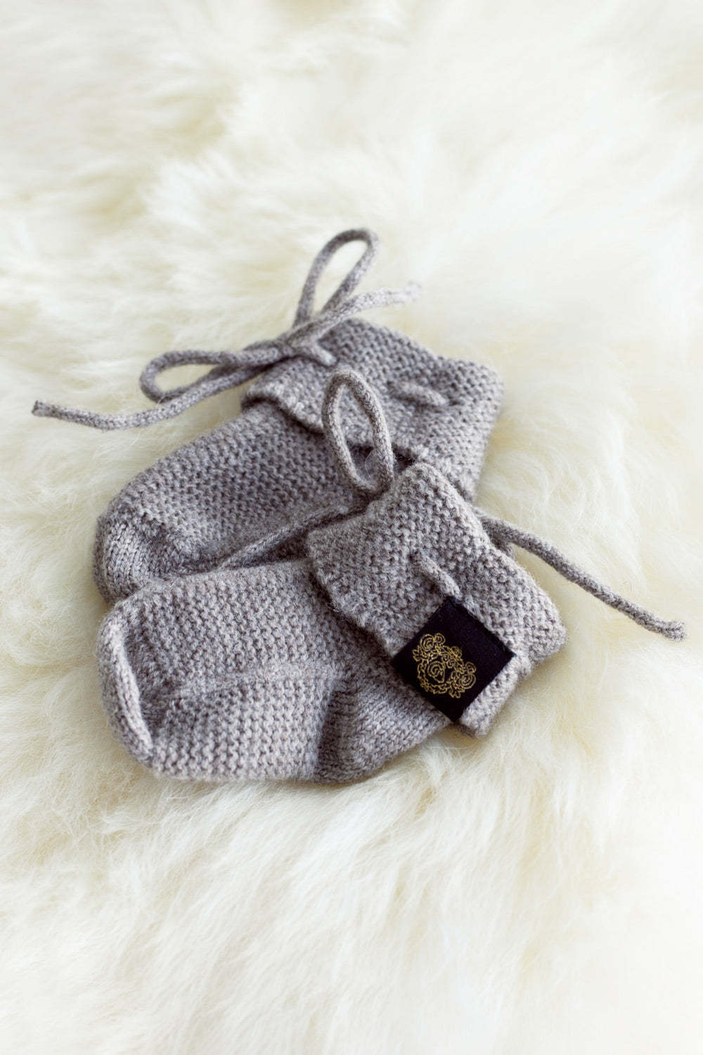 Merino Newborn Booties in Natural (Undyed) by McDonald on a white fur background