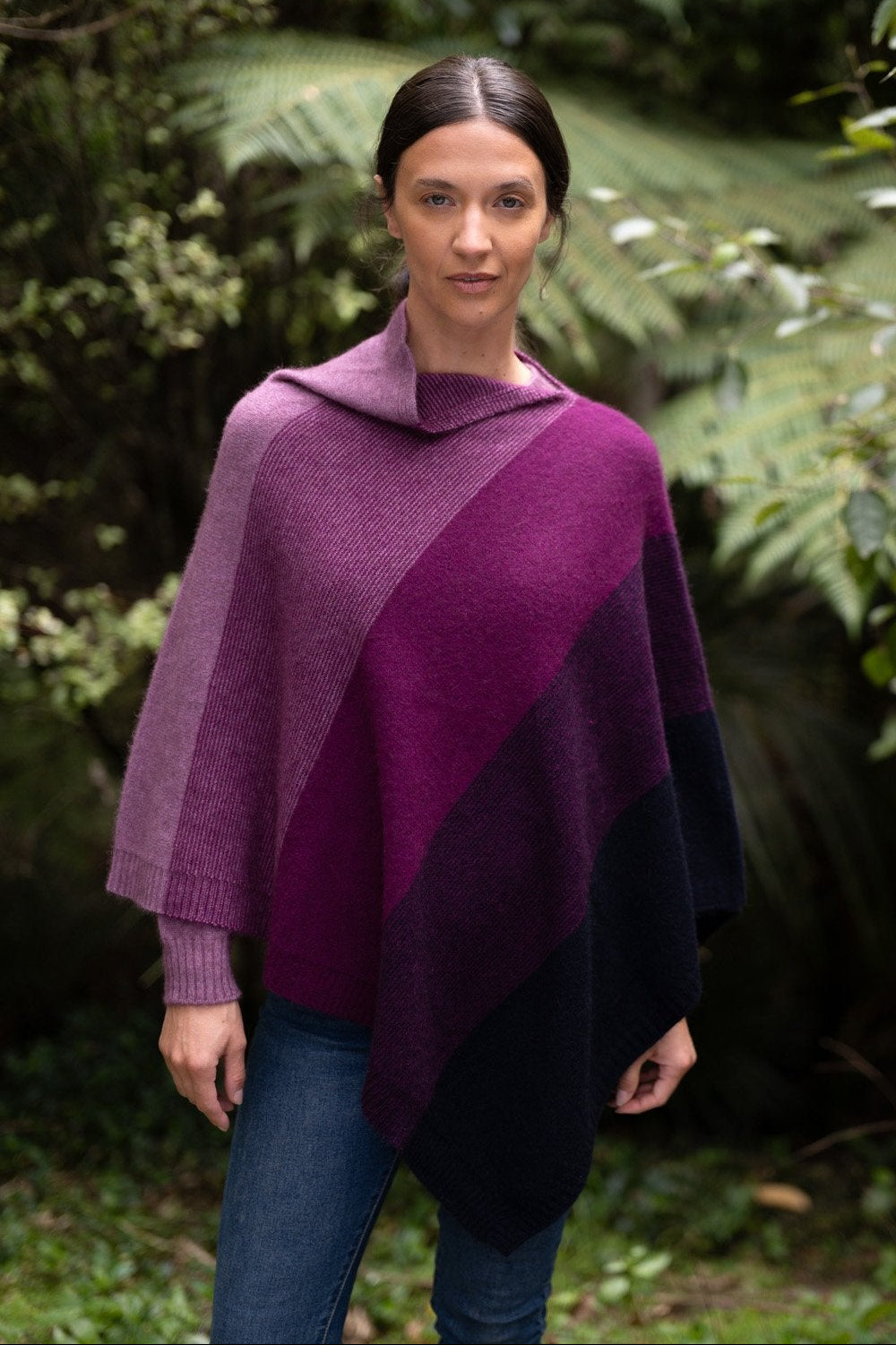 Woman wearing the Ombre Possum Merino Poncho in Amaranth by McDonald in a forest setting