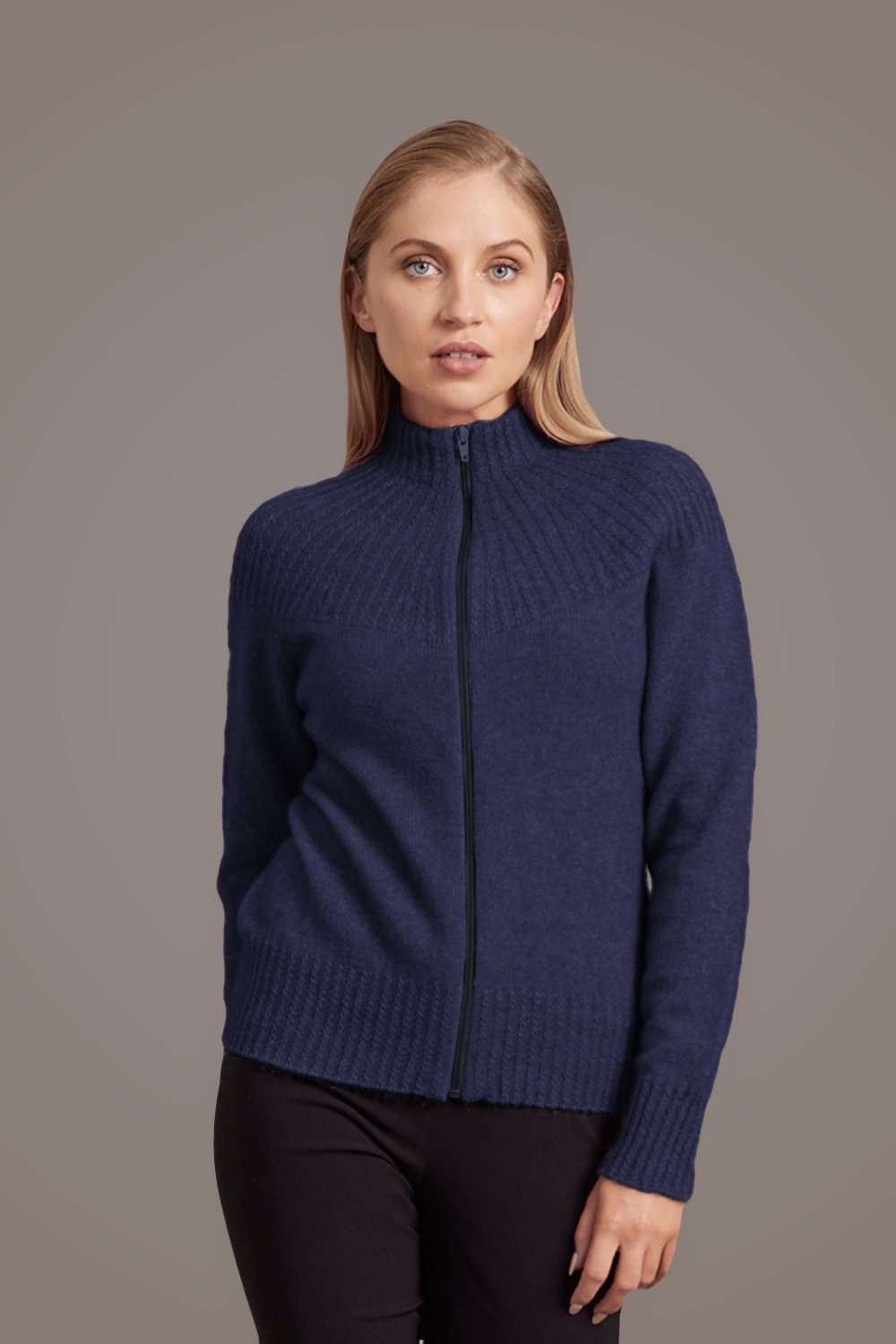 Woman wearing the Yoke Neck Cable Possum Merino Jacket in Navy by McDonald against a gray background