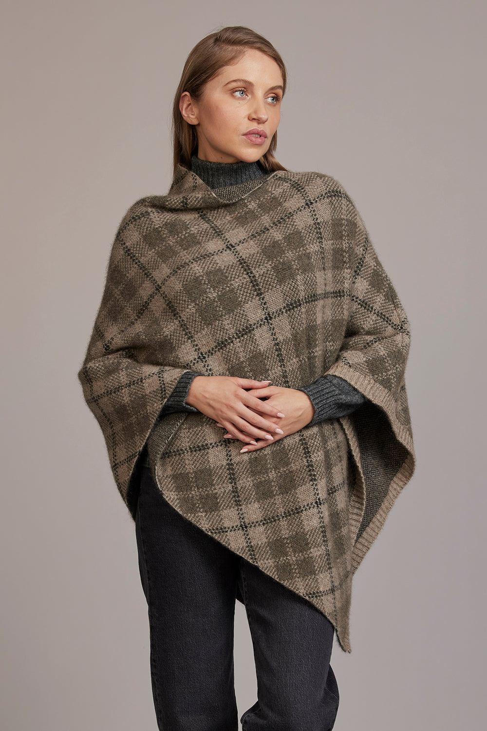 Woman wearing a plaid poncho against a plain background