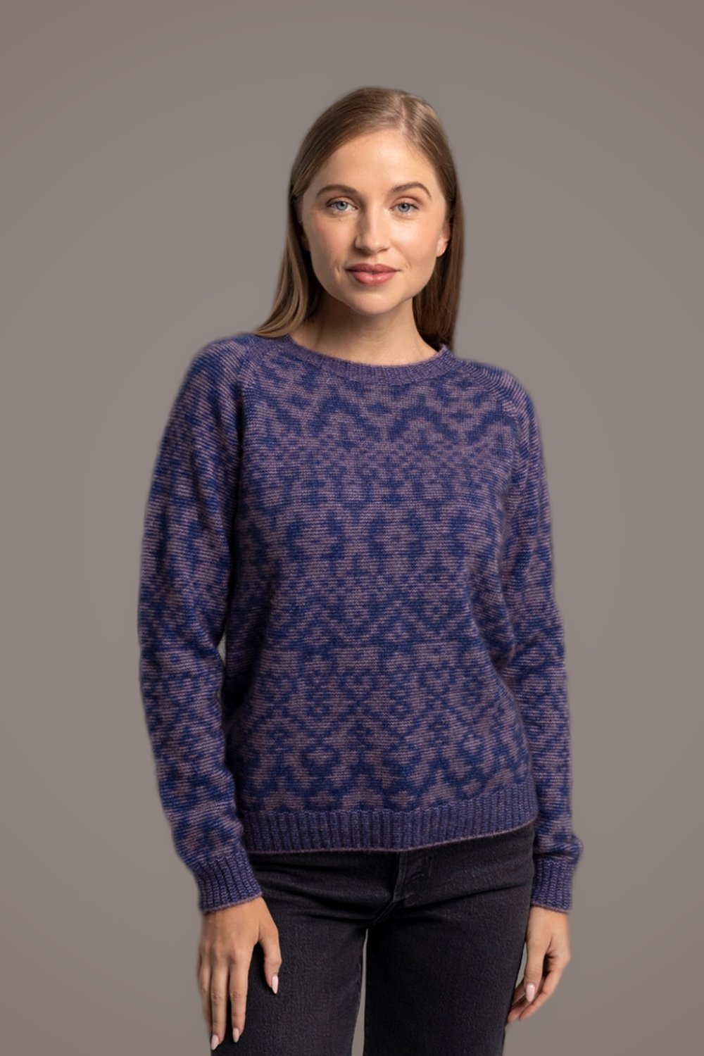 Woman wearing the Fair Isle Possum Merino Pullover in Lilac/Cobalt by McDonald against a gray background