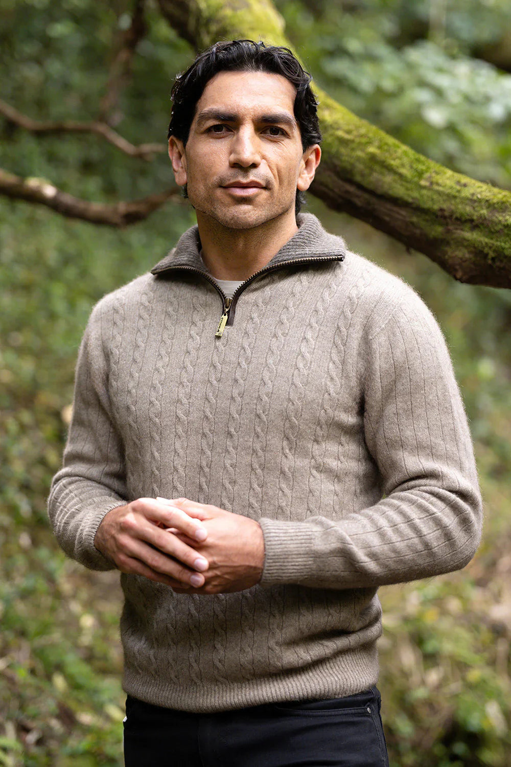 Man wearing the Cable Possum Merino Jersey with Contrast Trim in Mocha/Bark by McDonald standing in a natural setting with trees.