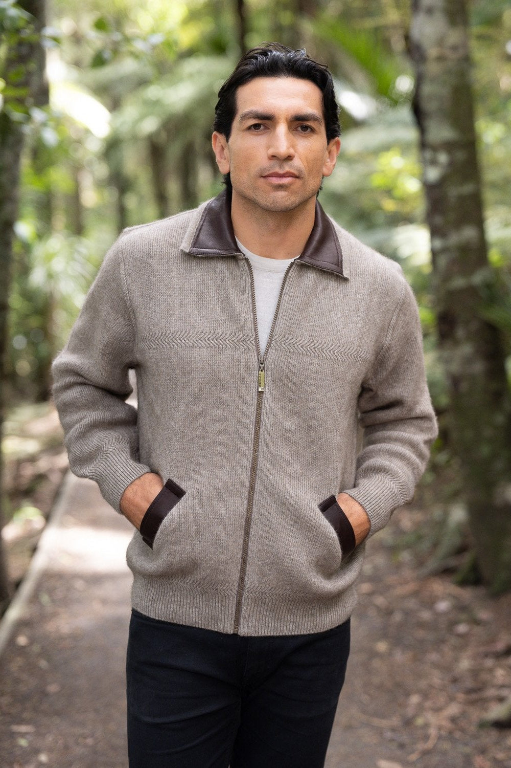 Man wearing the Lambskin Collar Possum Merino Jacket in Mocha by McDonald in a forest setting