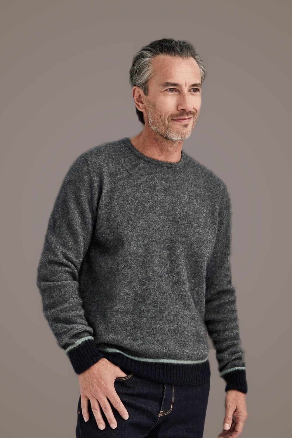 Man wearing the Horizon Possum Merino Sweater in Ash by McDonald and dark pants against a plain background