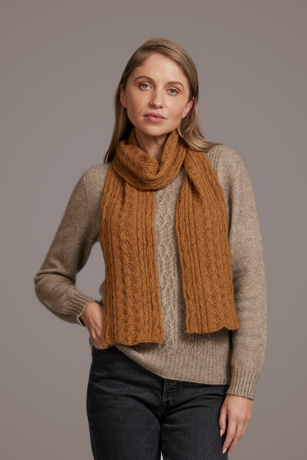 Woman wearing a brown sweater and the Cable Possum Merino Scarf in Honeycomb by McDonald against a plain background