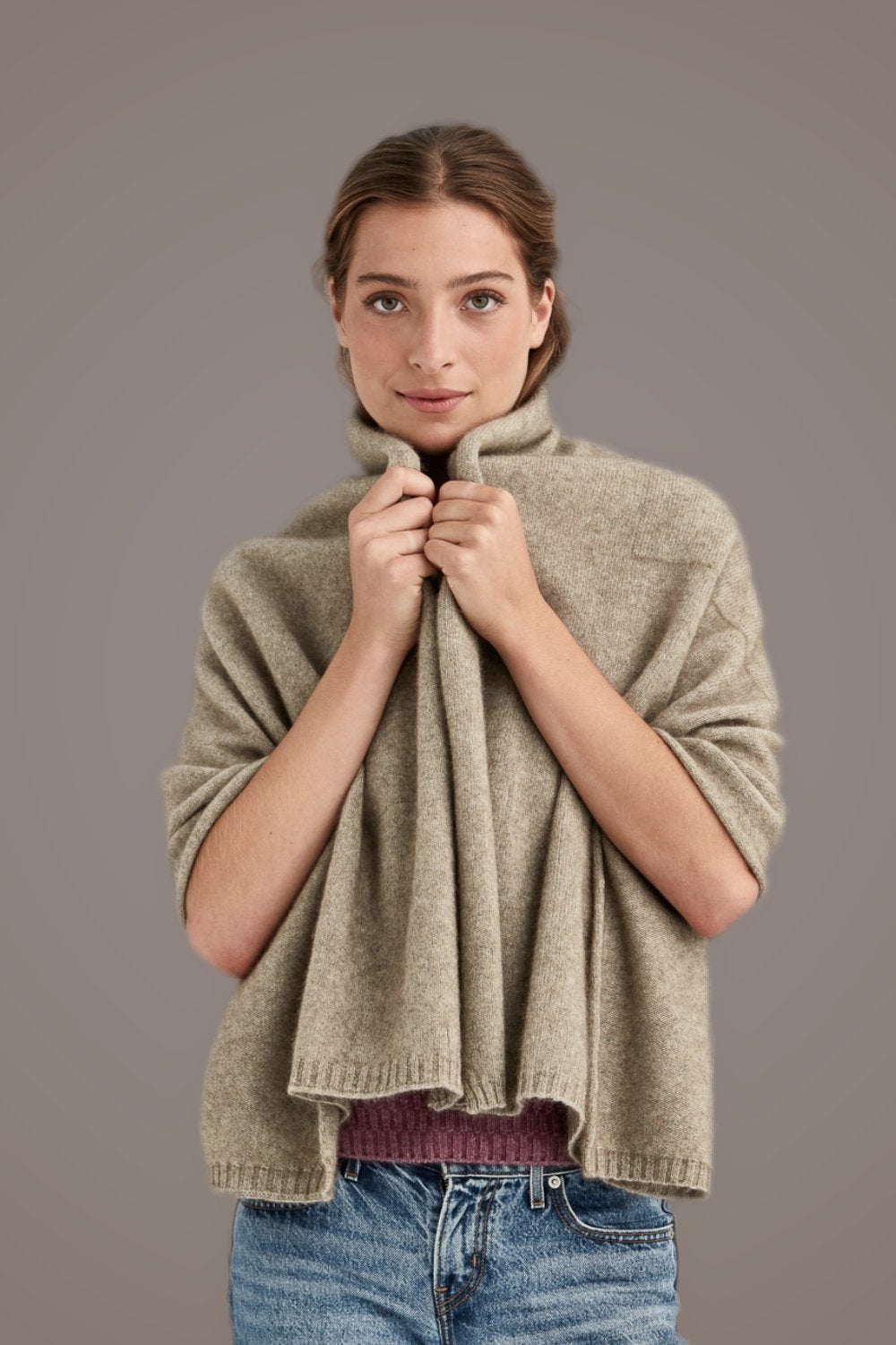 Woman wearing the Travel Possum Merino Throw in Mocha by McDonald with a plain background