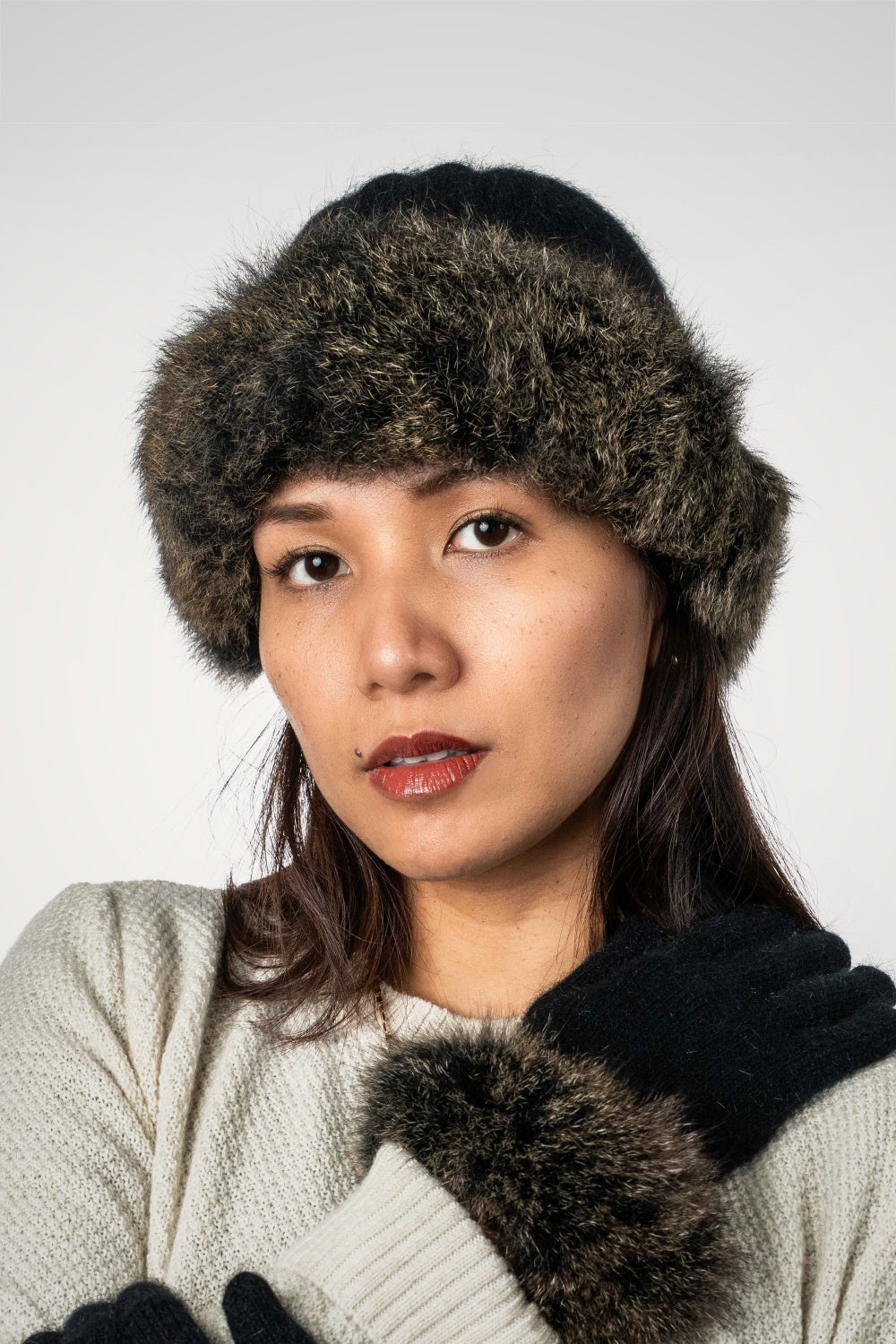 Woman wearing Fur Trim Possum Merino Beanie in Black/Snowtip by Koru with matching gloves against a white background