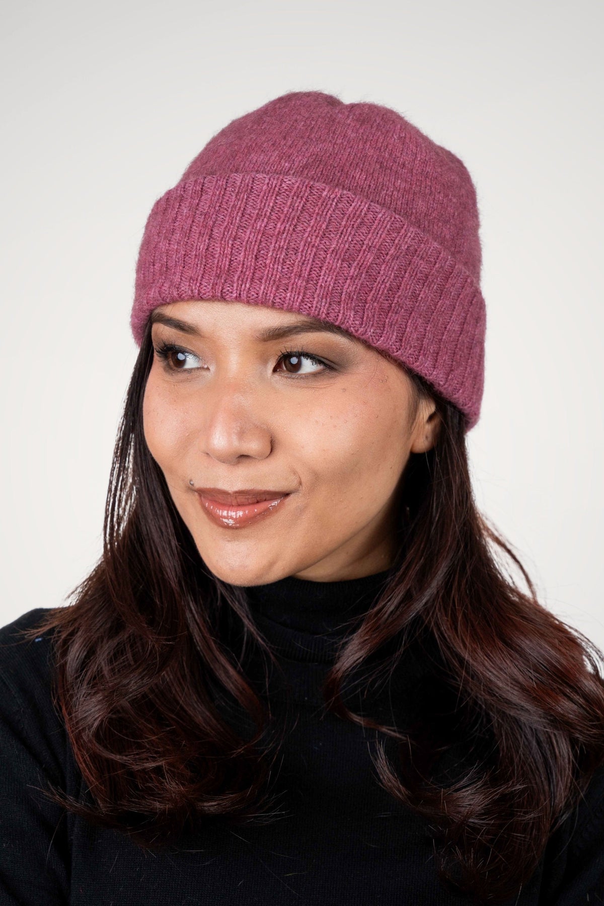 Woman wearing the Lightweight Possum Merino Beanie in Rose by Koru against a white background