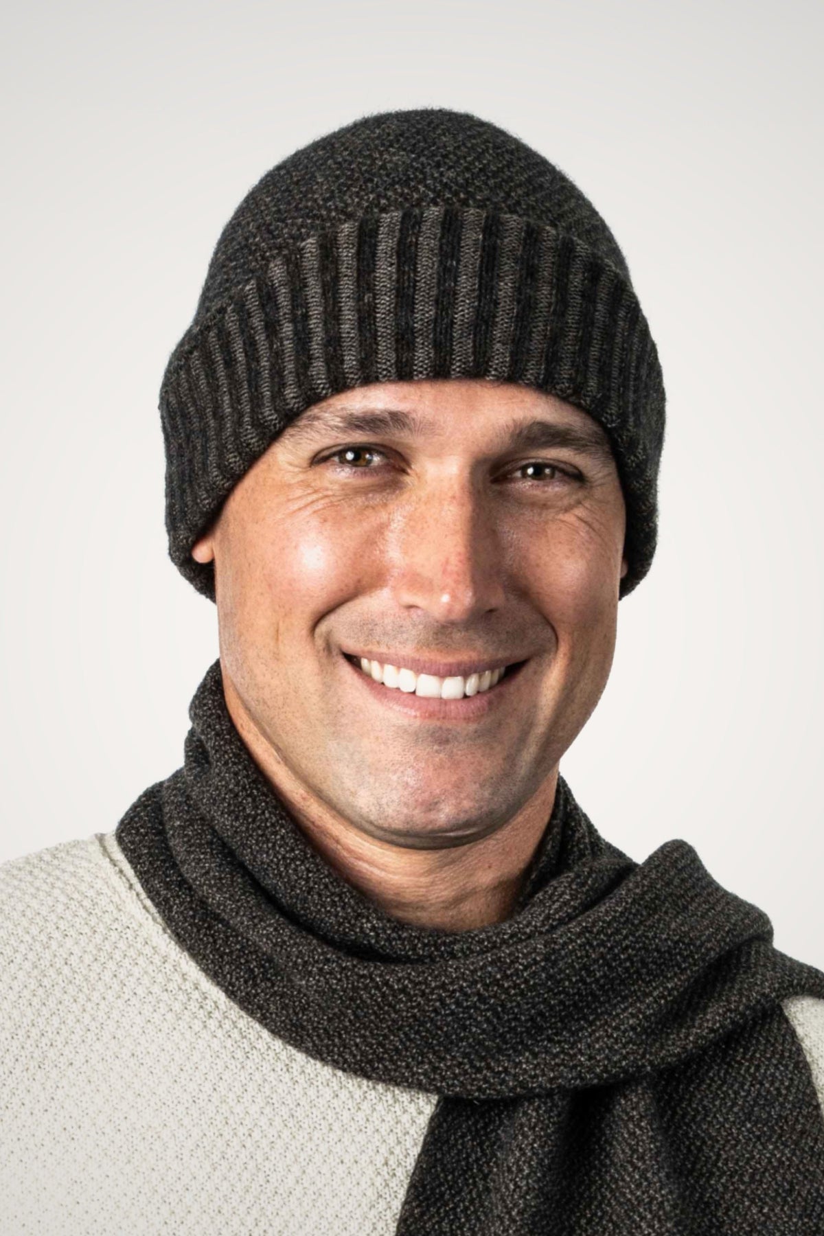 Man wearing the Moss Stitch Plated Possum Merino Beanie in Espresso/Suede by Koru with matching scarf against a white background