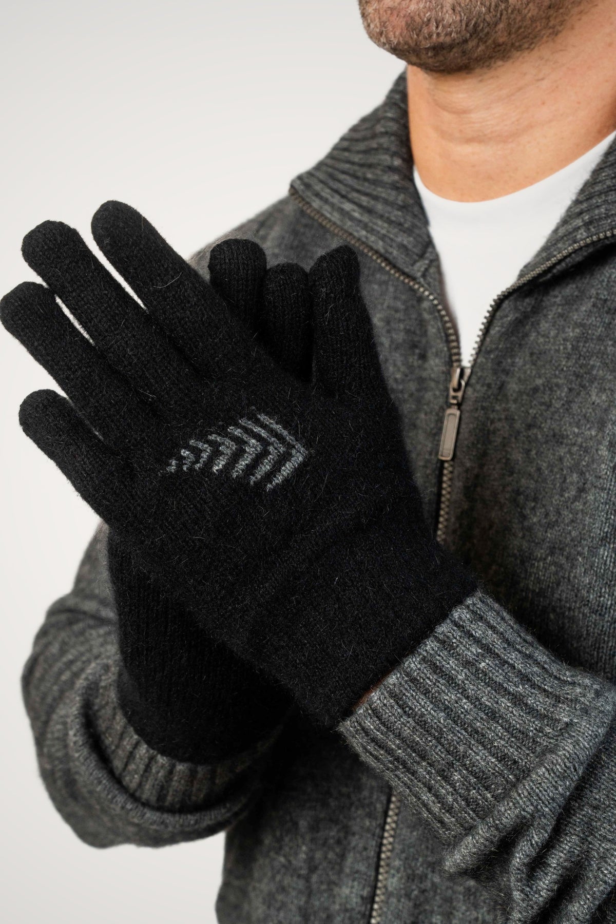 Fern Possum Merino Gloves in Black/Grey by Koru, worn by a man in a gray zip-up sweater.