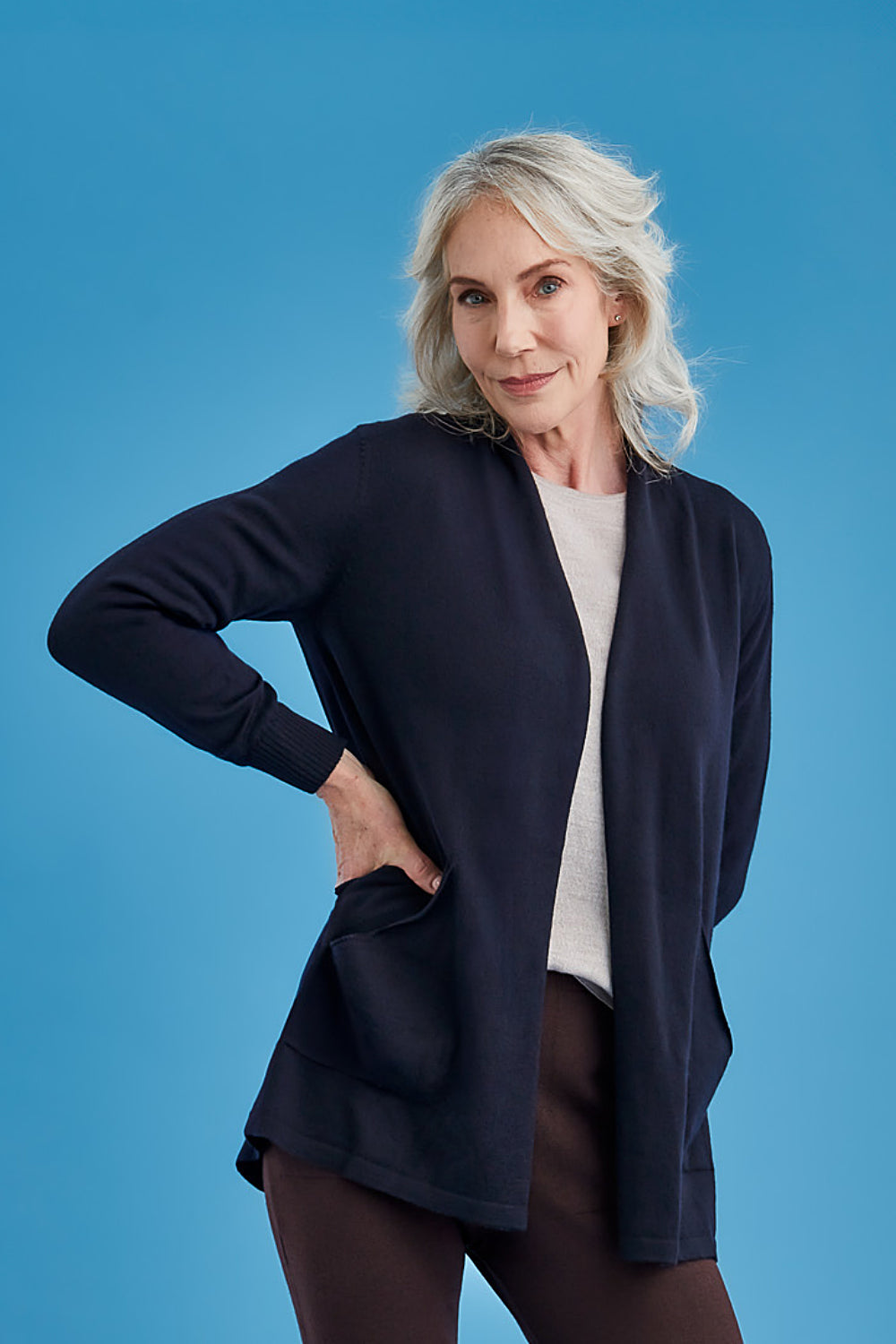 Woman wearing the Woman wearing the Open Front Merino Long Cardigan in Light Navy by Royal Merino on a blue background