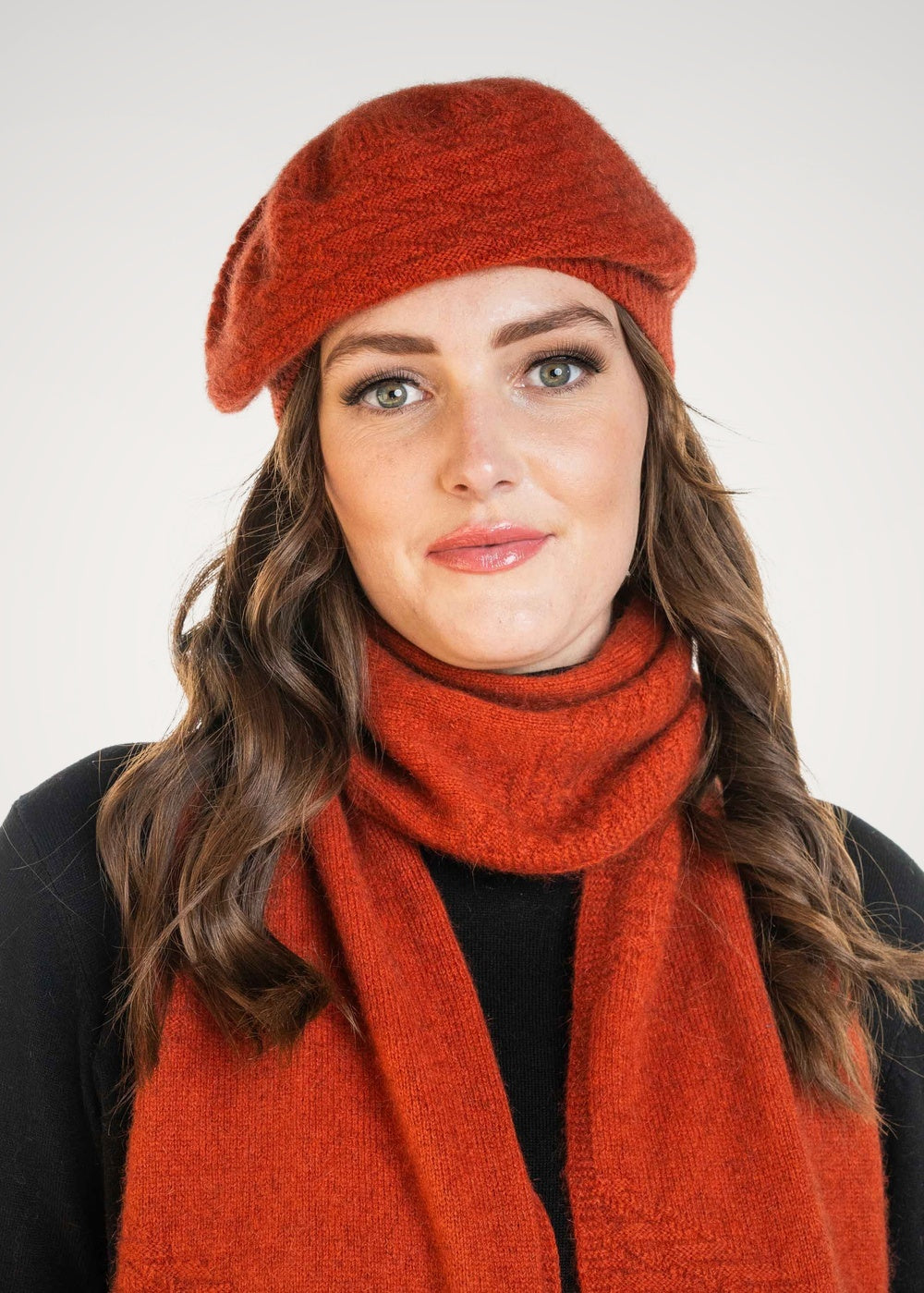 Woman wearing the Zig Zag Possum Merino Beret in Sienna with matching scarf by Koru against a white background