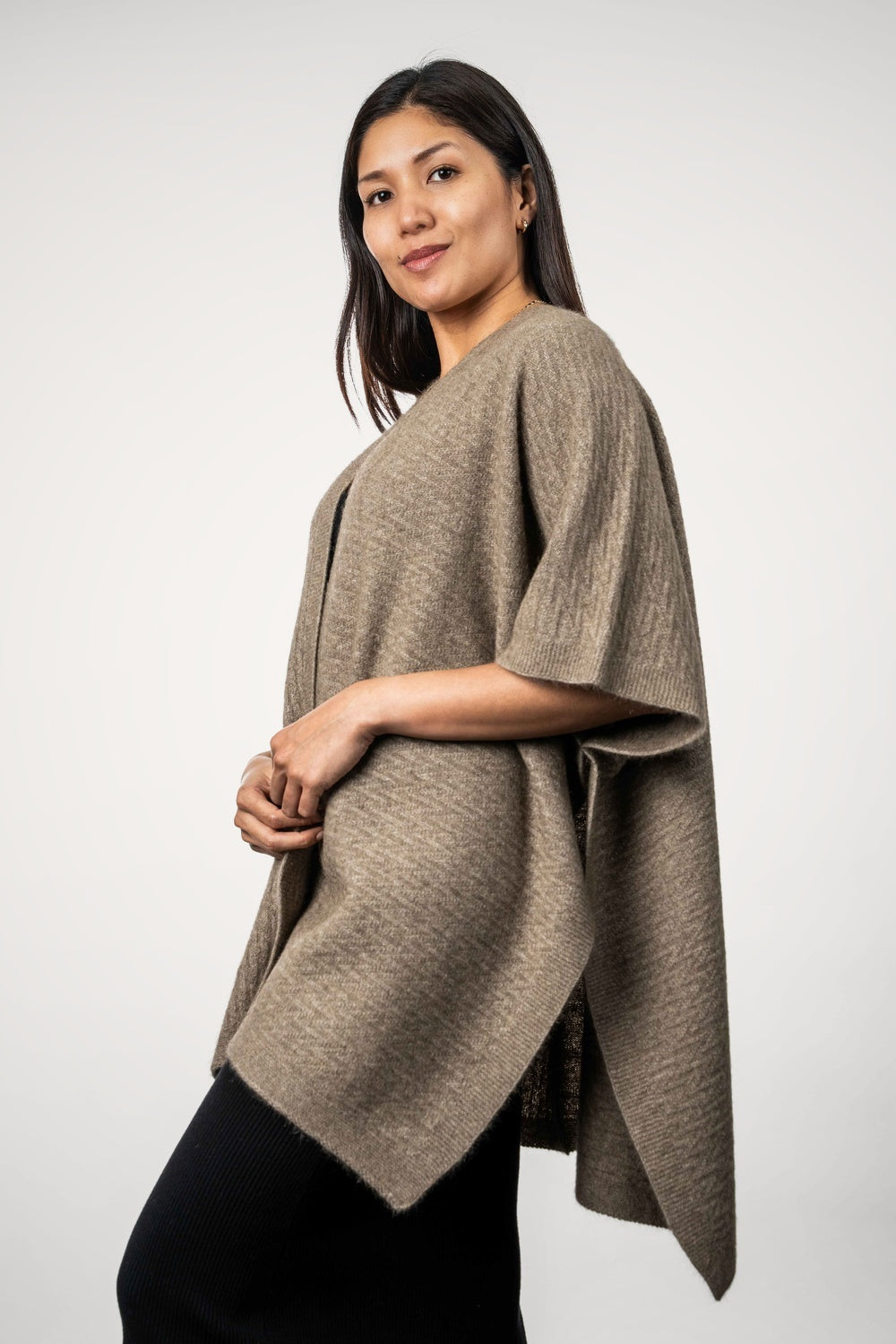 Woman wearing the Zig Zag Textured Possum Merino Cape in Mocha by Koru against a white background - side view