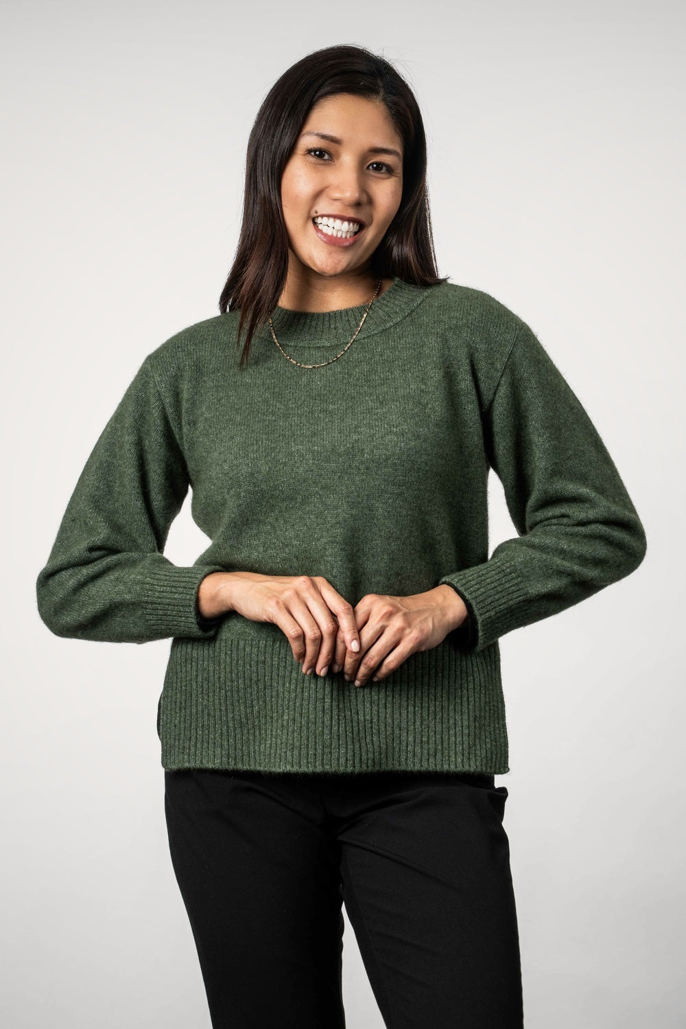 Woman wearing the Split Hem Possum Merino Jumper in Moss by Koru against a white background