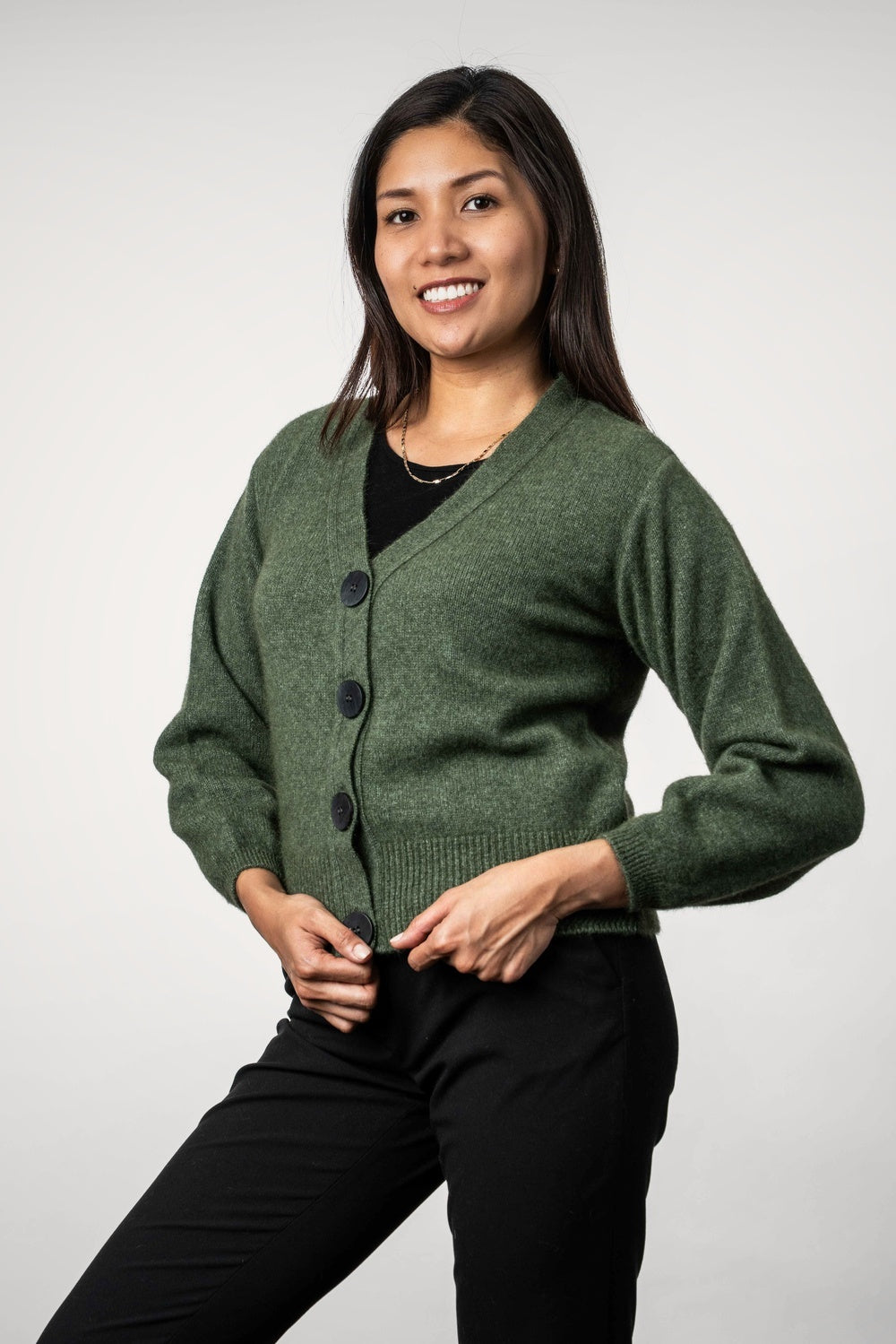 Woman wearing the V Neck Possum Merino Cardigan in Moss by Koru on a white background