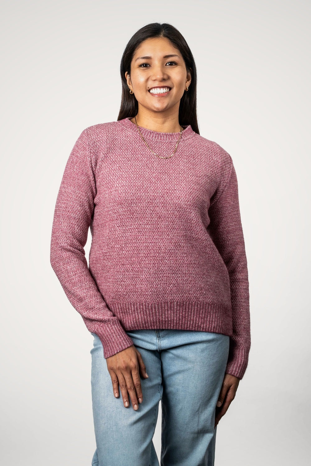 Woman wearing the Moss Stitch Plated Possum Merino Jumper in Rose/Natural by Koru with light blue jeans against a white background