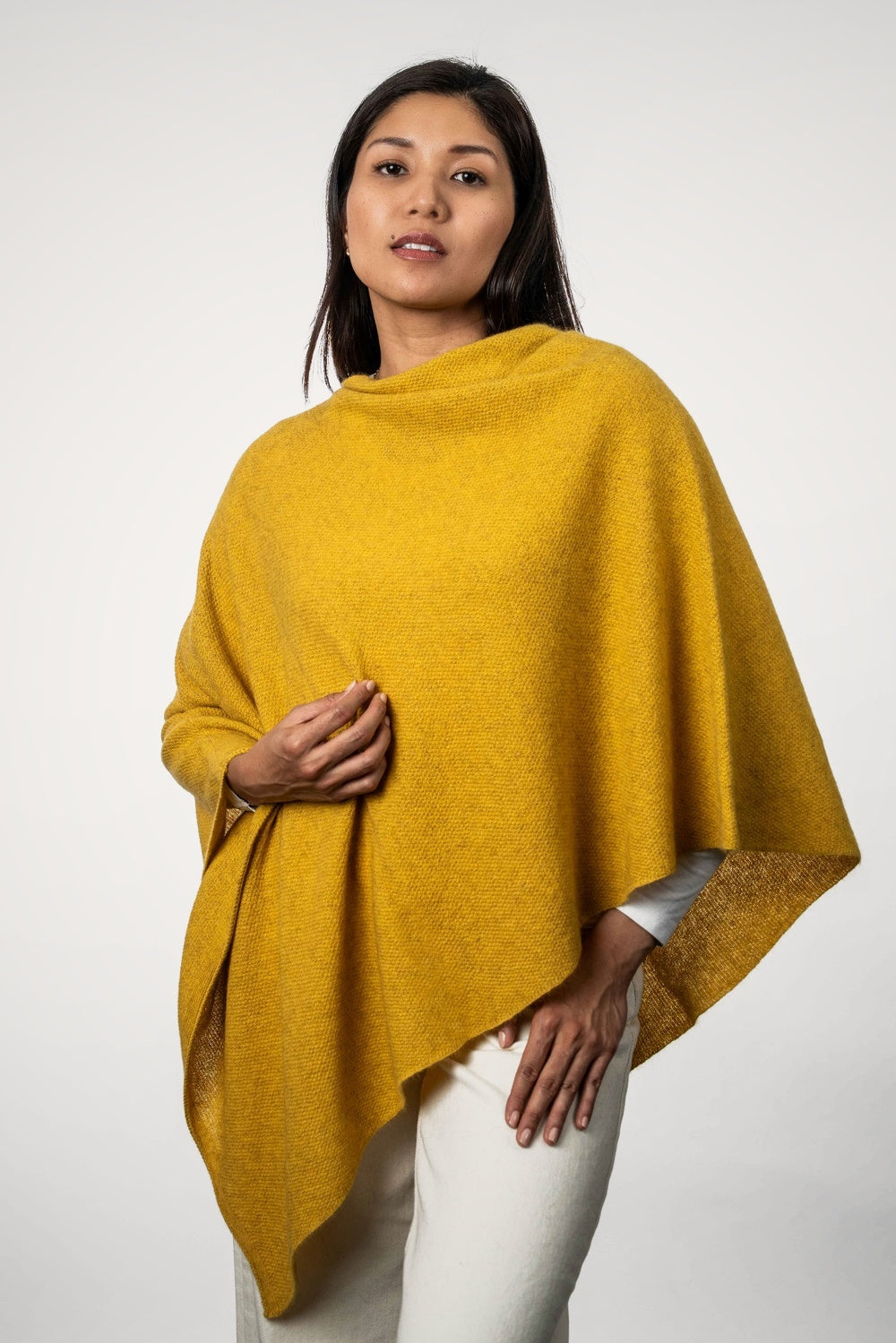 Woman wearing the Two Way Possum Merino Poncho in Kowhai by Koru against a white background