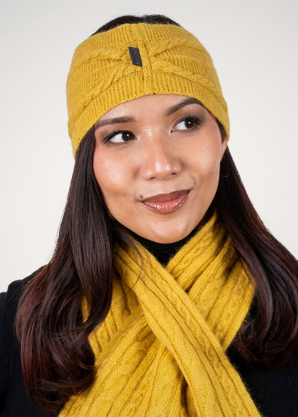 Woman wearing the Cable Possum Merino Headband in Kowhai by Koru with matching scarf against a white background