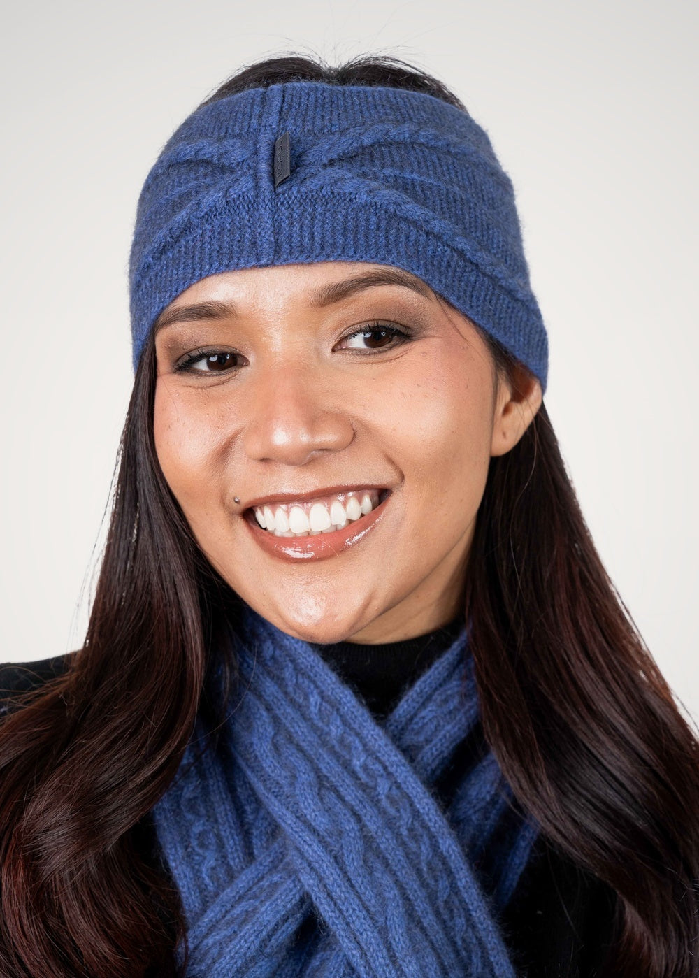 Woman wearing the Cable Possum Merino Headband in Periwinkle by Koru with matching scarf against a white background