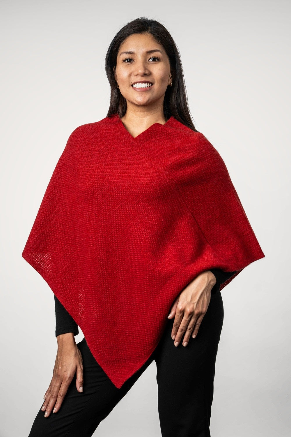 Woman wearing Moss Stitch Possum Merino Poncho in Scarlet by Trilogy against a white background