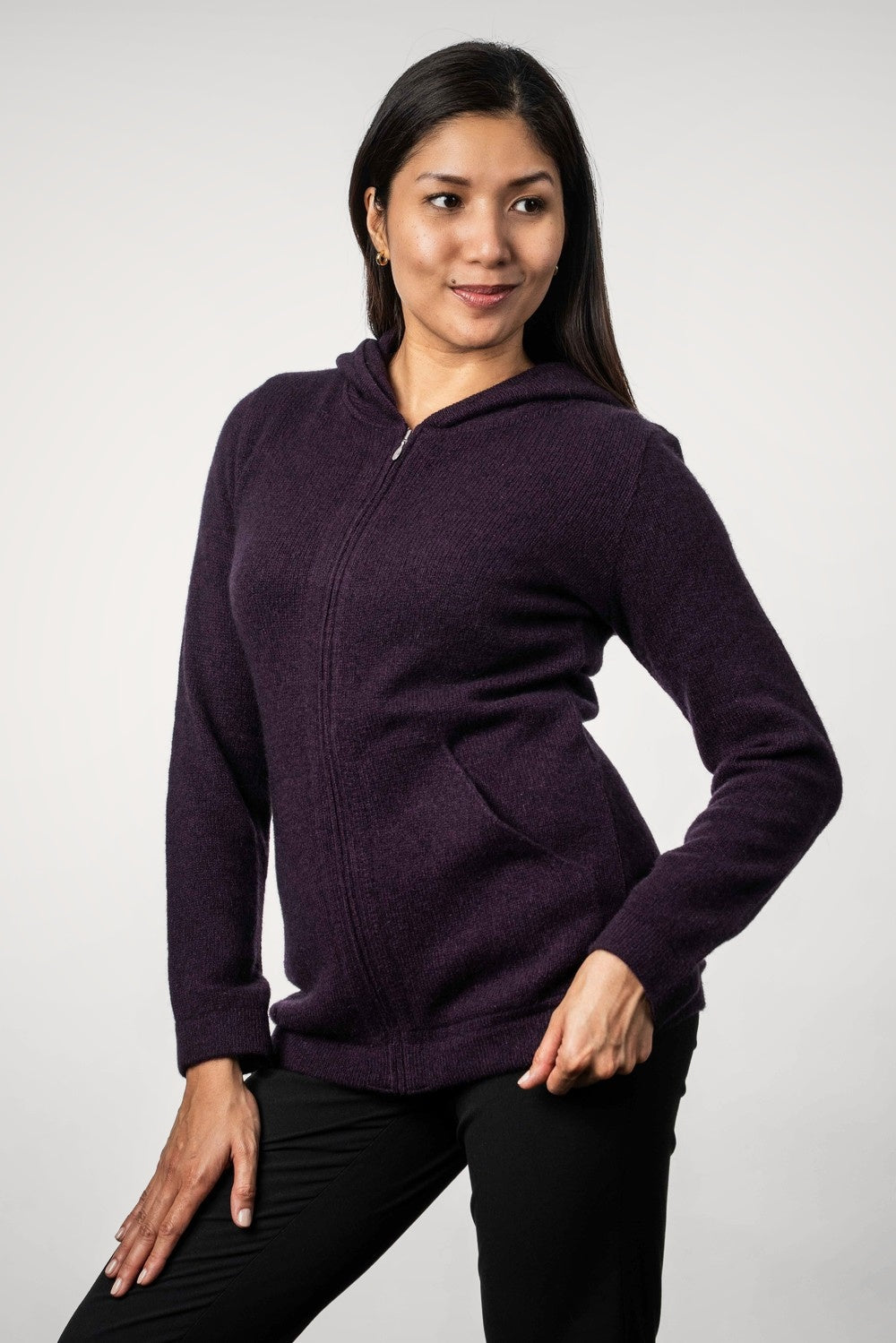 Woman wearing the Hooded Zip Possum Merino Jacket in Aubergine by Trilogy against a white background